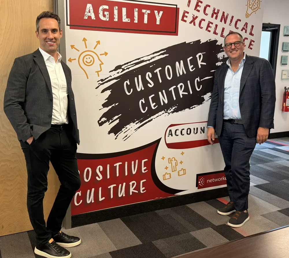 Network Doctor co-founders David Birk and Paul Hilbert in the Network Doctor office, in front of the company values wall